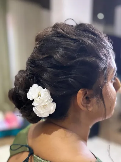 A side profile of the textured messy bun, adorned with a couple of simple white flowers. This shows how the style looks from all angles.