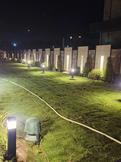 A wide view of the newly installed lawn and lighting system. The combination of a perfect green carpet and warm lighting creates an inviting and luxurious outdoor living area.