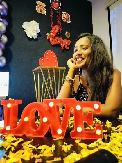 A birthday girl smiling brightly, sitting at a table decorated with flower petals and a 'LOVE' sign.
