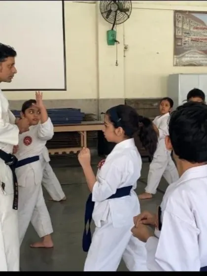 An instructor corrects a young student's blocking technique. One-on-one attention is a key part of our teaching method, helping each student refine their movements and understand the purpose behind them.