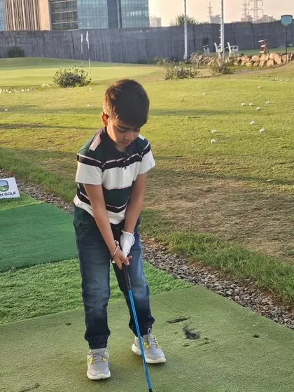 A young golfer focuses on his stance during a practice session. My goal is to help every child find their rhythm and confidence on the driving range.