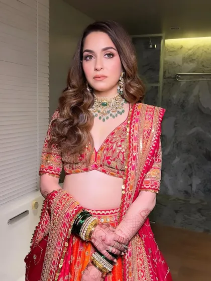 The complete look for this bride's wedding day. The combination of a traditional red and orange lehenga, classic jewelry, and my signature glowing makeup creates a look that is both timeless and breathtaking.