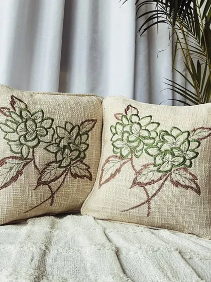 A subtle and elegant green floral embroidery on a natural cotton base. This design brings a sense of calm and tranquility to any space.
