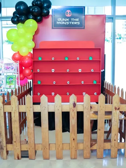 A wider view of the 'Dunk the Monsters' game booth, enclosed by a picket fence for a clean and organized setup.