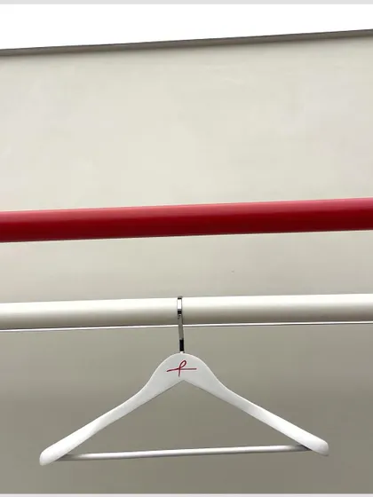 Simplicity in detail. The clean white hangers with the red ARKS logo hang from a sleek display rod, reflecting the brand's focus on elevated essentials.