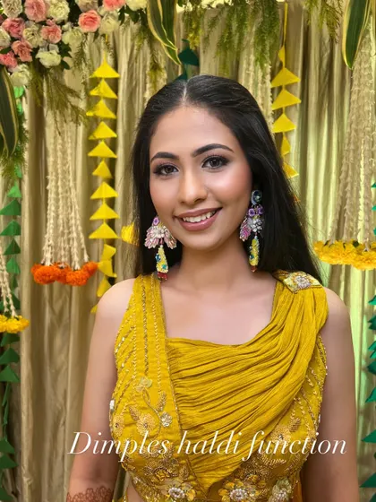 A portrait of the bride at her Haldi ceremony. The makeup is understated and elegant, allowing her colorful earrings and outfit to shine.