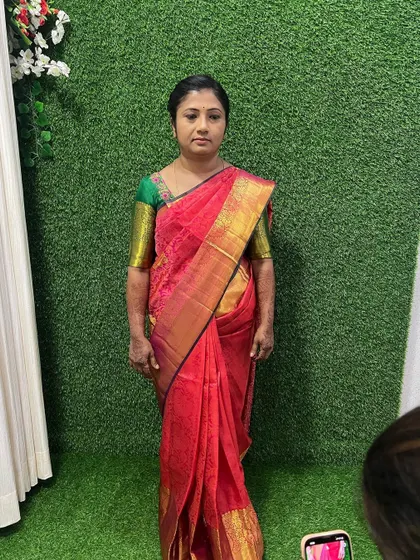 A full length view of the simple makeup look. The makeup is subtle and natural, ensuring the client looks and feels comfortable while beautifully complementing her traditional pink and green saree.