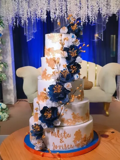 This is the biggest wedding cake I've made, weighing 25 kgs! It's a five-tier masterpiece with Dutch truffle and rum plum cake, decorated with handmade wafer paper peonies and delicate gold leaf accents.