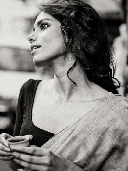 A black and white street portrait of a model in a saree, holding a traditional clay 'bhar' of tea. This shot captures a slice of everyday Kolkata life with a touch of cinematic grace.