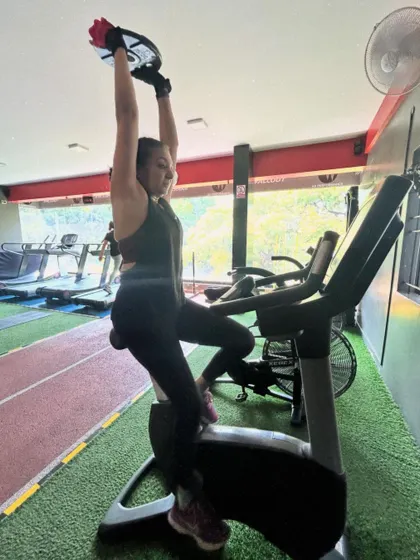 A client performs a weighted step-up on a stationary bike, a creative and challenging variation to build leg strength.