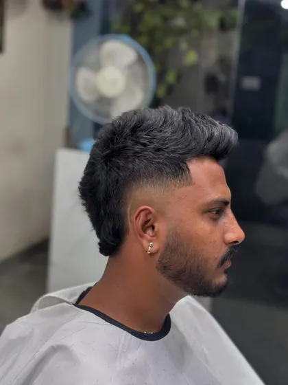 A side profile of a textured mohawk, which is a variation of the modern mullet. The hair is kept longer along the center of the head, creating a spiky, eye-catching silhouette.