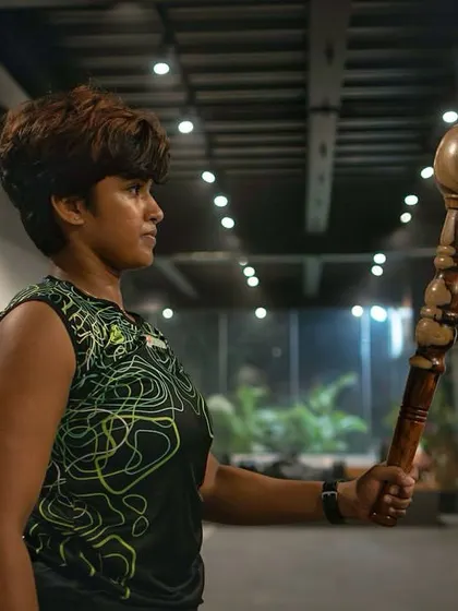 A female member holds a Gada with a look of intense focus. This image tells a story of dedication and the journey towards achieving personal fitness goals with us.