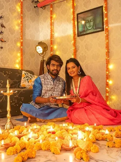 A classic portrait from a festive Diwali photoshoot. The couple is holding a plate of diyas, looking at the camera, making for a perfect picture to share with family and friends.