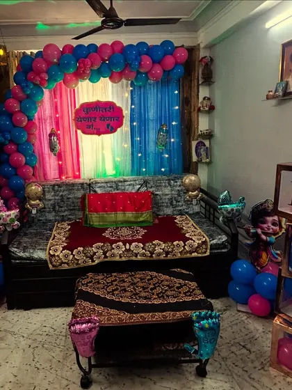 A complete house party setup for a baby shower. We transformed the living room with a colorful drape backdrop, a balloon arch, and themed elements like 'BABY' blocks and character cutouts.