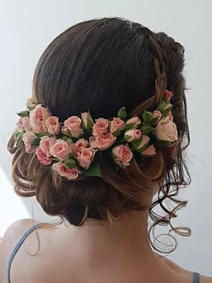 A romantic updo featuring a crown of fresh pink roses, showcasing how to incorporate real flowers into hairstyles.