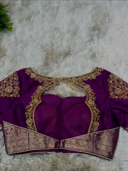 A purple blouse with a unique back design, featuring a cut-out framed by gold embroidery and a traditional zari border at the waist.