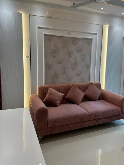 A custom-designed dusty pink sofa with channel tufting, set against a feature wall with elegant wallpaper and vertical light panels. This piece demonstrates our ability to create soft, contemporary seating.