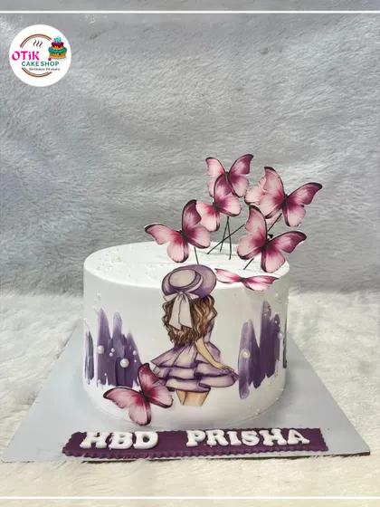 A whimsical birthday cake featuring a hand-painted girl surrounded by fluttering purple butterflies. It's a beautiful and artistic design for a special day.