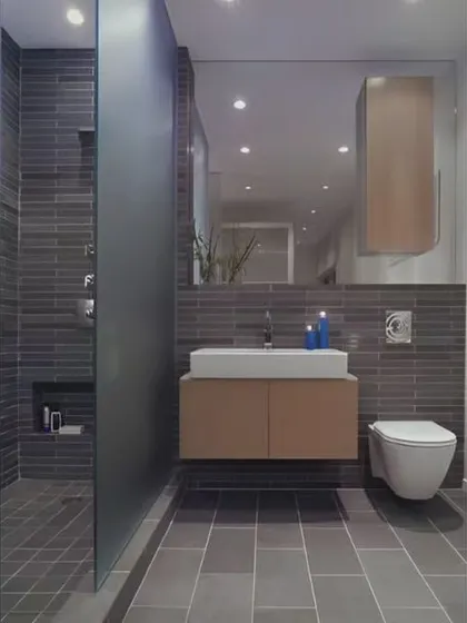 This bathroom features dark grey slate tiles in the shower and on the floor. A simple floating vanity and a large mirror help to keep the space feeling open and functional.