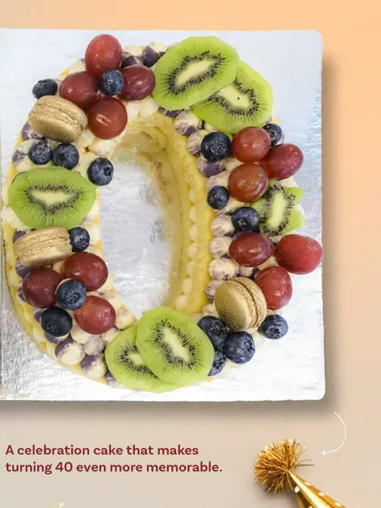 Celebrating a milestone like turning 40 deserves a special cake. This "40" shaped tart-cake is made with layers of cookie and cream, topped with fresh kiwi, grapes, blueberries, and delicate golden macarons.