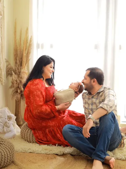 The father joins in, gazing at his newborn with adoration. This candid-style shot captures a genuine moment of connection between the new family.