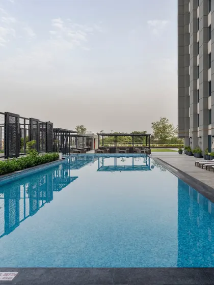 The hotel's rooftop swimming pool offers a serene escape with a view of the horizon. The clean lines of the pool deck and the modern pergola structures create a perfect space for relaxation.