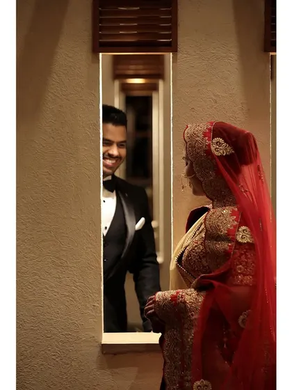 A creative and intimate shot of the groom looking at his bride through a narrow window. This artistic composition adds a unique and personal touch to their wedding album.