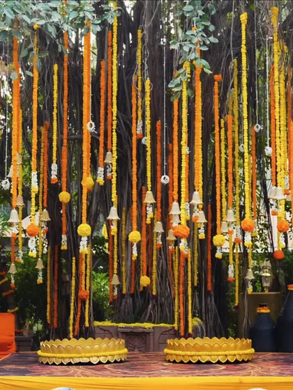 I love using natural spaces to create something truly special. For this outdoor Haldi, I used long, hanging strings of fresh marigolds and temple bells from a large tree to create a breathtaking backdrop that felt both grand and organic.