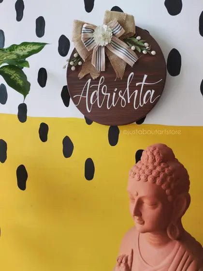 The "Adrishta" name plaque styled next to a terracotta Buddha statue in our studio, showing how our art complements a space of peace and tranquility.