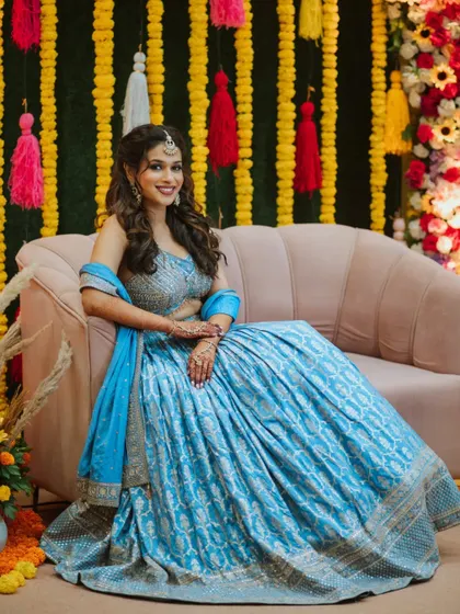 A lovely portrait of the bride seated against a vibrant marigold backdrop, a classic decoration for Indian pre-wedding events.