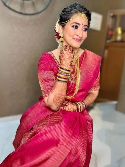 The perfect bridal glow. This bride's happiness shines through with her soft glam makeup, featuring a pink lip and shimmering eyes that complement her beautiful pink silk saree and henna.