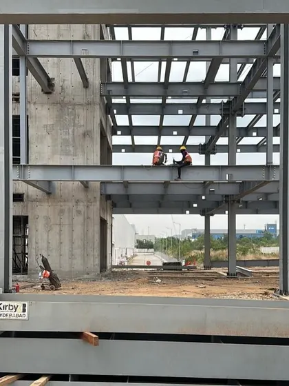 Workers on the steel frame of the ePositive campus. This image captures the human element of construction and the scale of the project, where the raw structure begins to define the vast, open spaces of the future research labs.