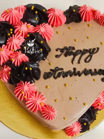A heart-shaped Dutch truffle cake with pink and black floral piping, perfect for an anniversary.