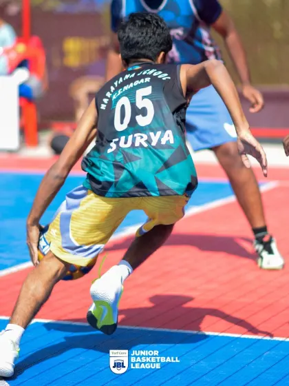 A low-angle shot of a player executing a crossover dribble. The action at the Junior Basketball League is fast-paced and exciting.