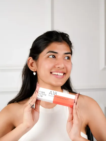 A bright, happy lifestyle portrait of a model holding the skincare product. Her genuine smile and radiant skin connect the brand with feelings of confidence and self-care.