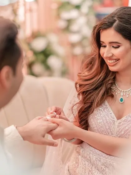 The bride smiles as she places the ring on her groom's finger, captured from a beautiful, intimate angle.