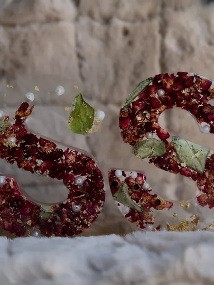 A closer look at these stunning alphabet lamps made with deep red rose petals. The combination of the rich floral color, delicate pearls, and shimmering gold flakes creates a truly luxurious and romantic effect.