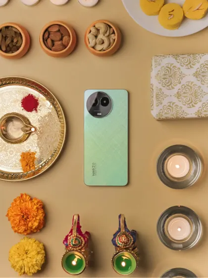 A flatlay composition for Diwali featuring the realme Narzo phone, traditional sweets, diyas, and other festive elements.