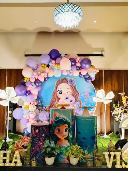 A mermaid-themed birthday setup for a joint celebration, featuring marquee numbers '4' and '2' and custom printed pedestals.