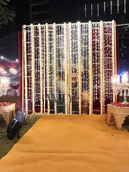 A unique photo backdrop featuring a mirrored wall with hanging floral strings and elegant crystal candelabras, creating a glamorous and interactive spot for guests.
