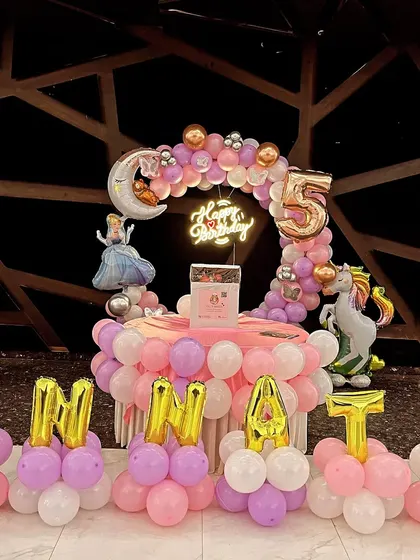 A princess-themed 5th birthday with Cinderella and unicorn figures, and the name spelled out in foil balloons.