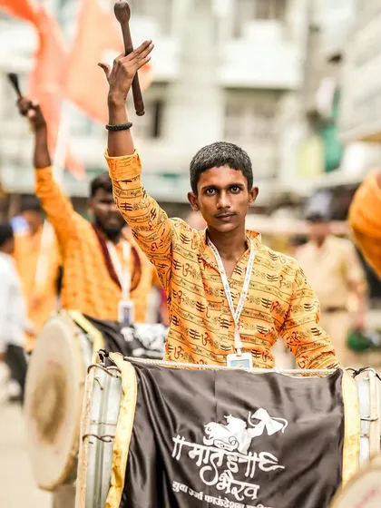 The color version of the young dhol player, his orange shirt bright and festive.