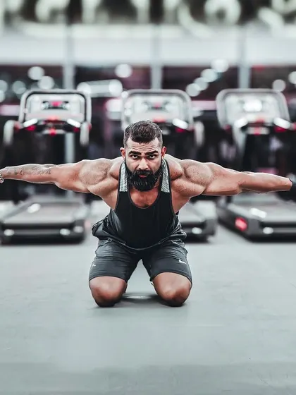 A powerful kneeling pose in front of the treadmills. If your goals don't challenge you, they won't change you. This pose displays upper body mass and conditioning.