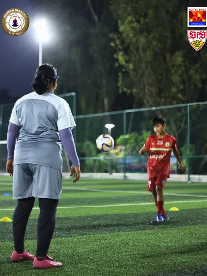 A female coach guides a young player during a drill. We believe in the importance of female role models in coaching and are proud to have them as part of our team, mentoring the next generation.
