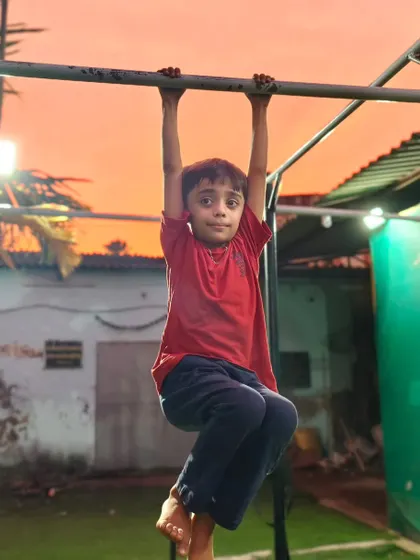 This young athlete is building a strong foundation by practicing his knee-tuck hang, a progression towards L-sits.