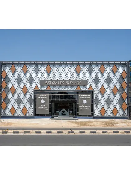 The facade of the Satyam Four Wings retail showroom in Shimoga. We used an industrial approach with a diagrid pattern of metal perforated sheets and ACP cladding to create a modern and visually striking exterior.
