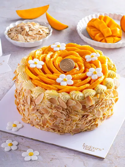 Our signature Fresh Cream Mango Cake, adorned with a beautiful rosette of hand-sliced Alphonso mangoes and delicate sugar flowers. This cake is a celebration of seasonal perfection, with toasted almonds adding a delightful crunch.