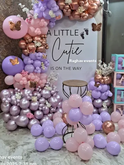 A detailed shot of a pastel-themed baby shower decoration. You can see the mix of lavender and pink balloons, chrome accents, and butterfly details on the custom backdrop.