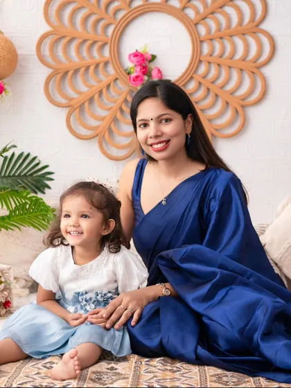 A serene mother and daughter portrait. The mother's elegant blue saree complements the daughter's dress, creating a beautiful and coordinated look.
