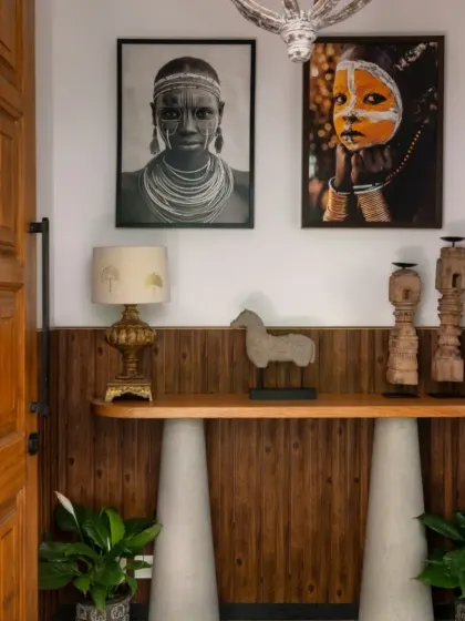The entryway at Villa Shai sets a tone of rustic elegance, featuring a console table with concrete-finish legs and a wooden top, adorned with tribal art and artifacts. This space received an Honourable Mention at the International Design Awards (IDA).